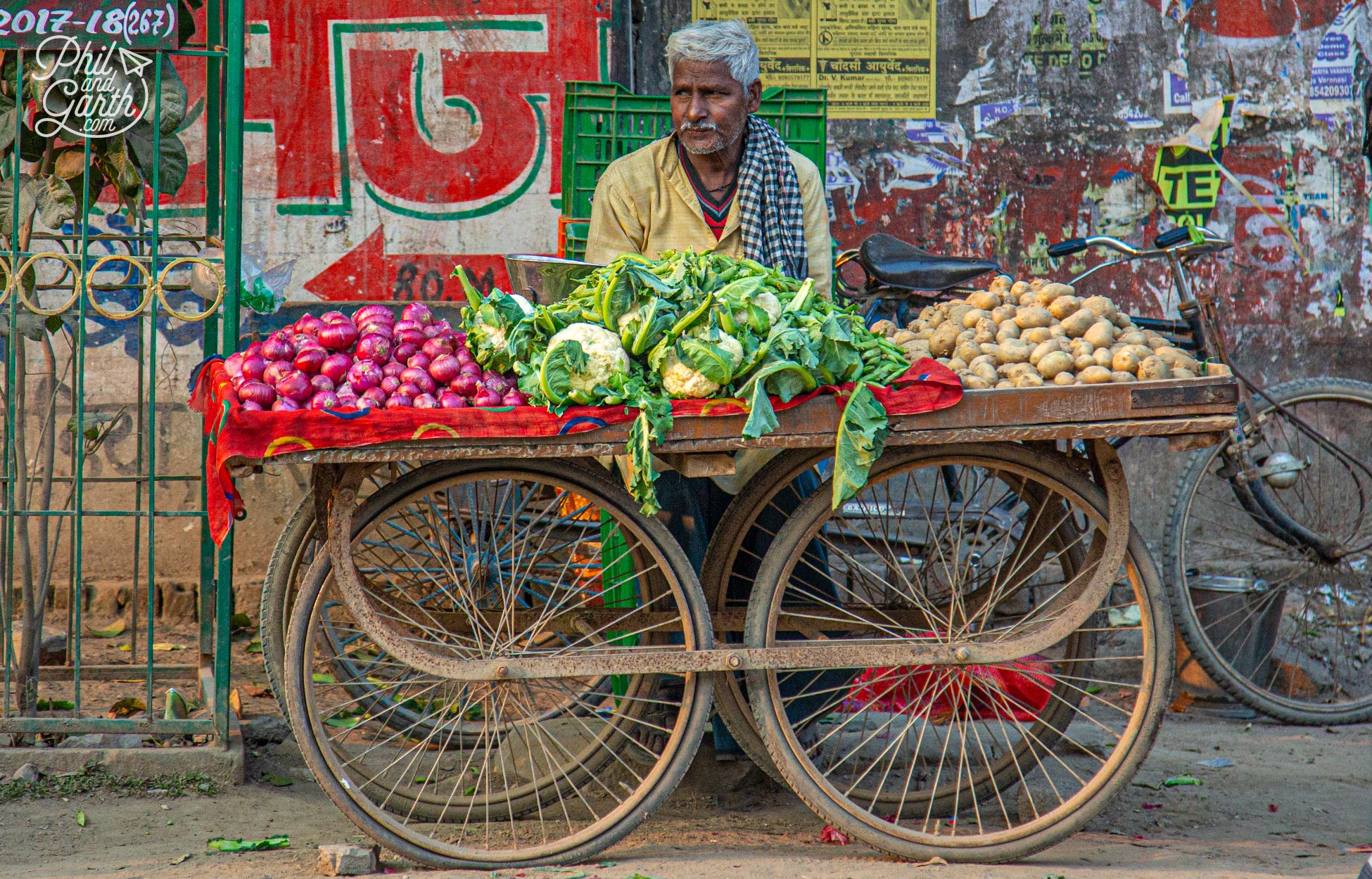 A guy selling onions, cauliflowers and potatoes