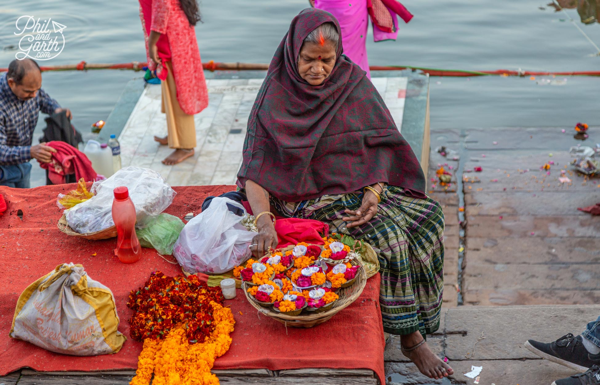 A lady makes candle and flowering offerings for the evening aarti