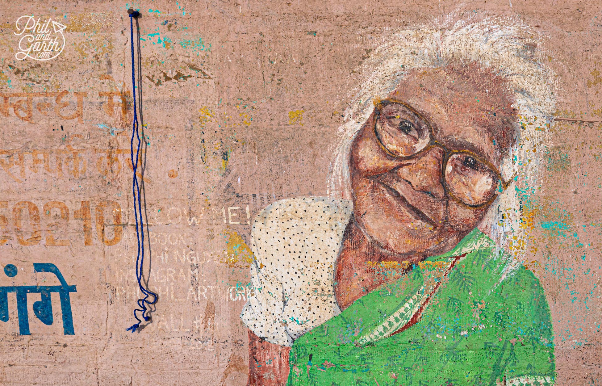 Street art in Varanasi - mural of an old lady on a pink wall