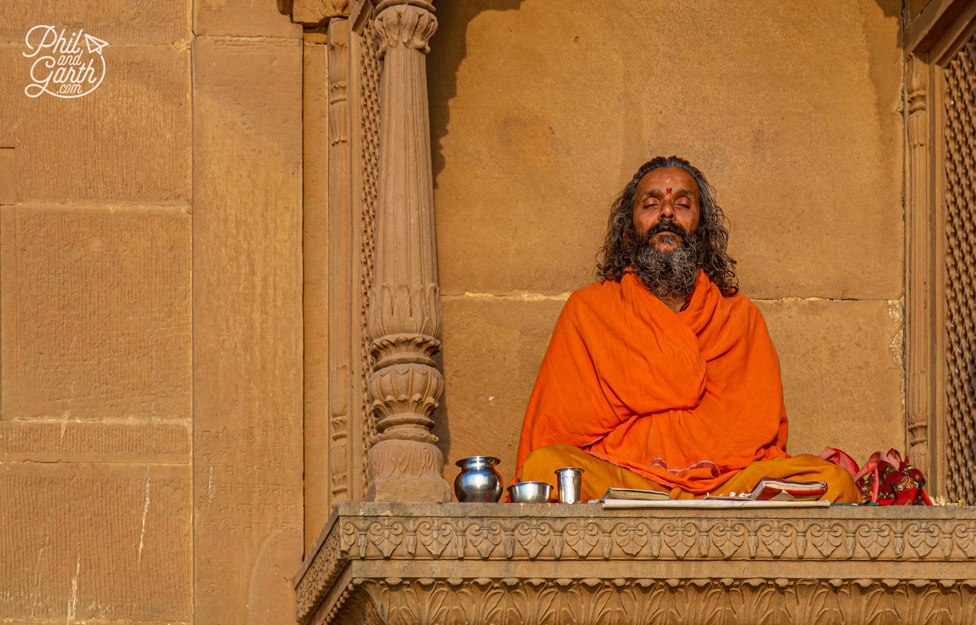 A sadhu meditating next to a temple