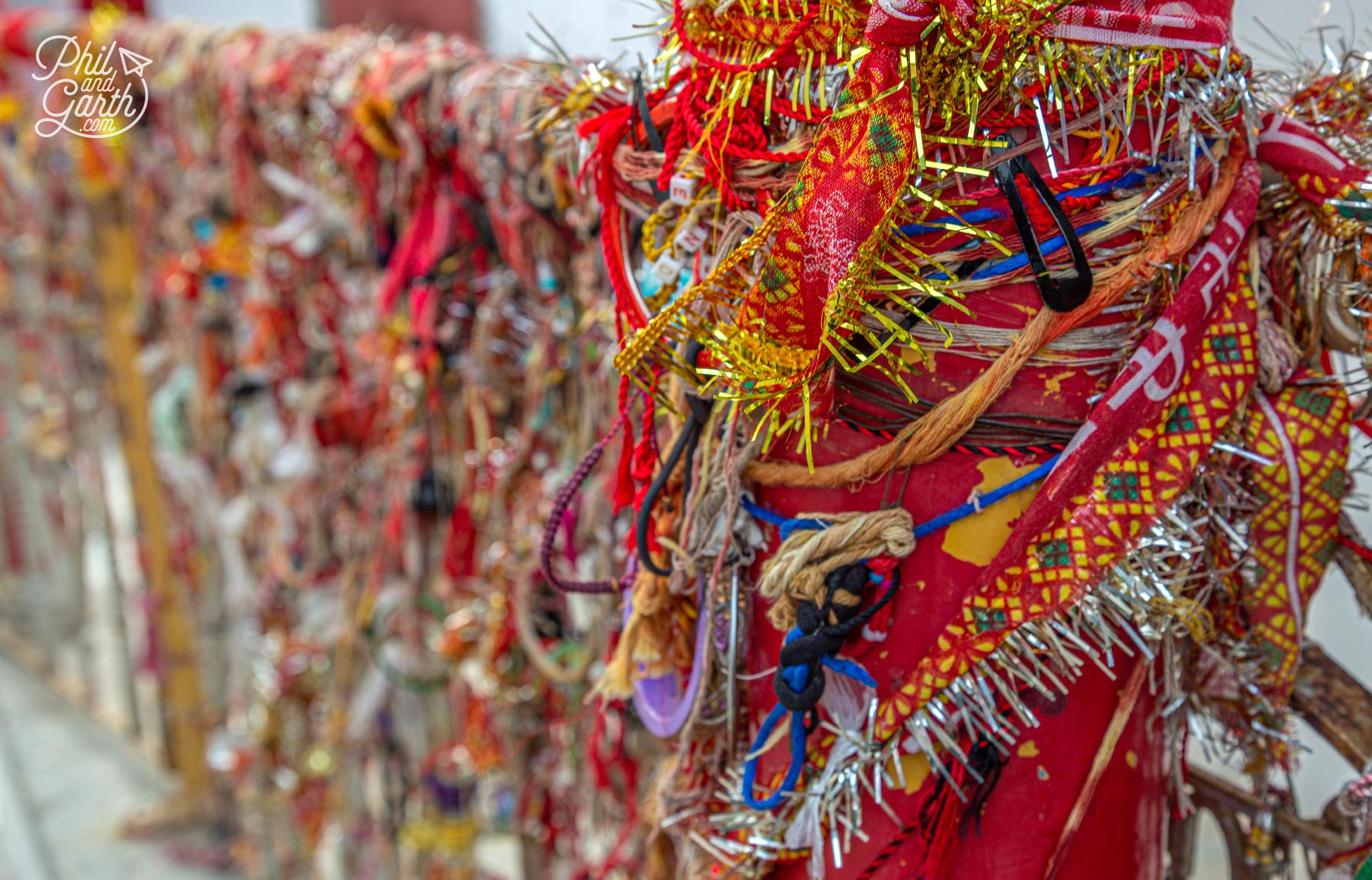 Hundreds of bracelets and strings of tinsel are tied to the temple's fence