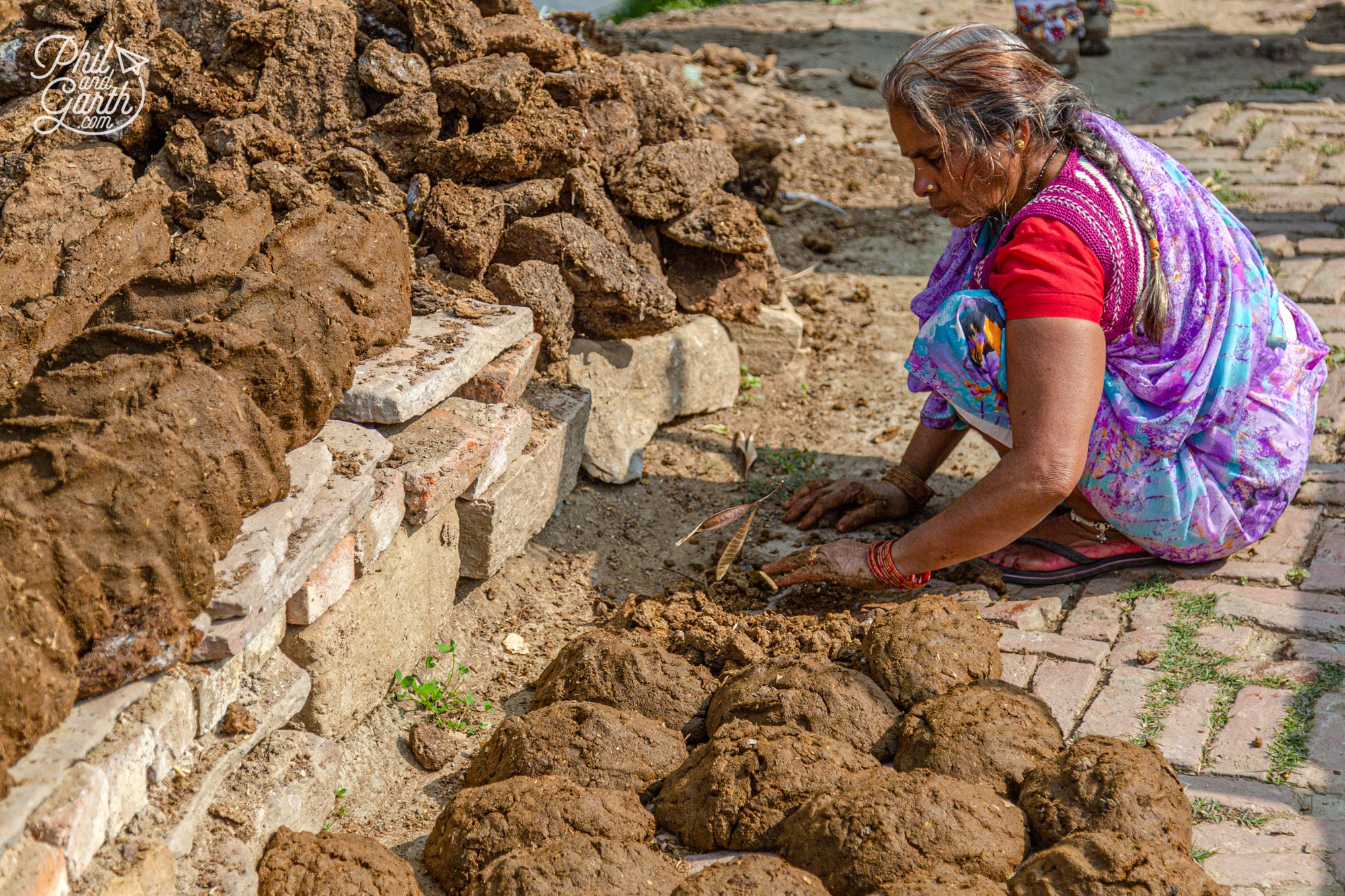 A lady making 'Dung cakes' from cow dung, which are dried and used as fuel
