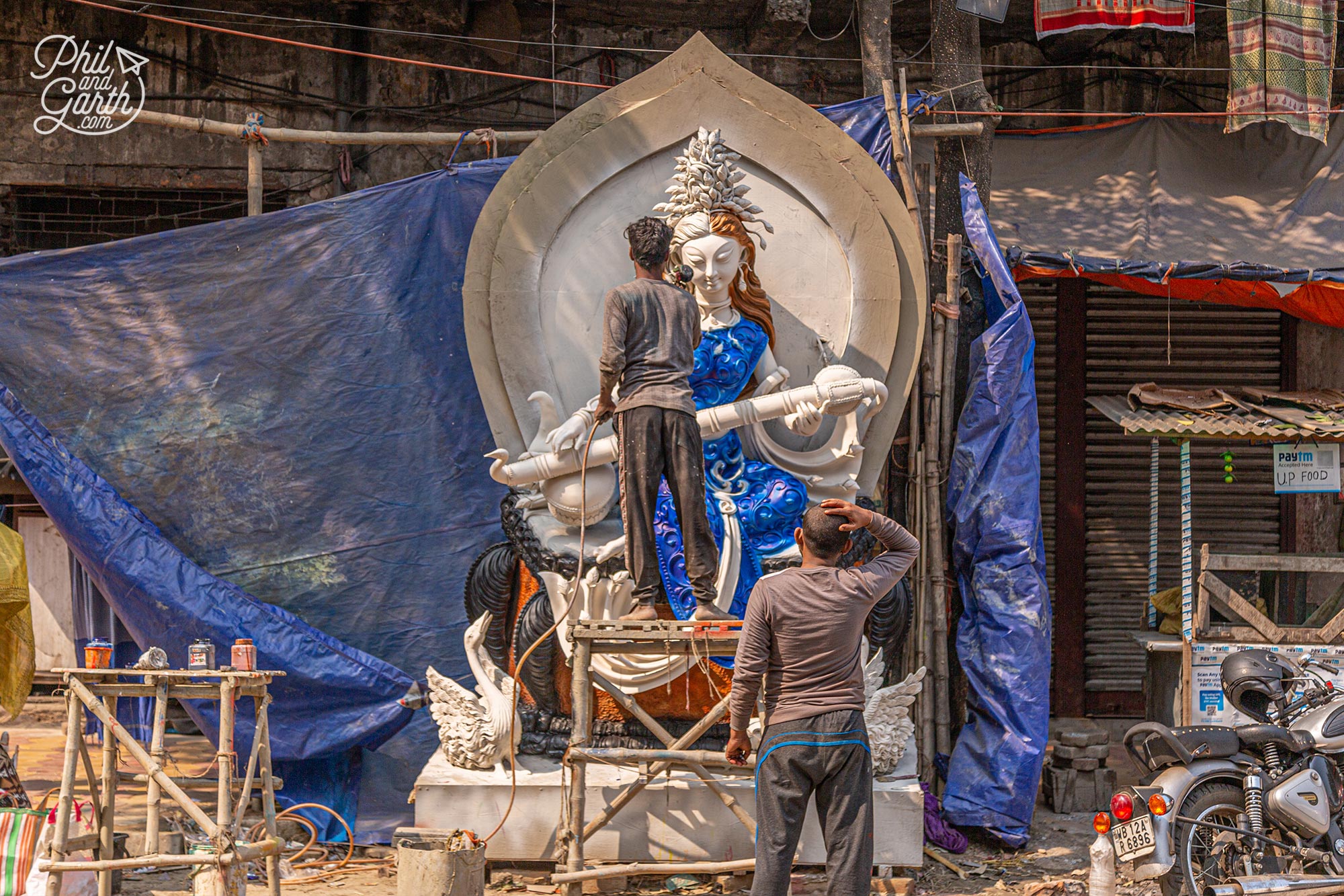 An artist airbrushing a large statue on the street