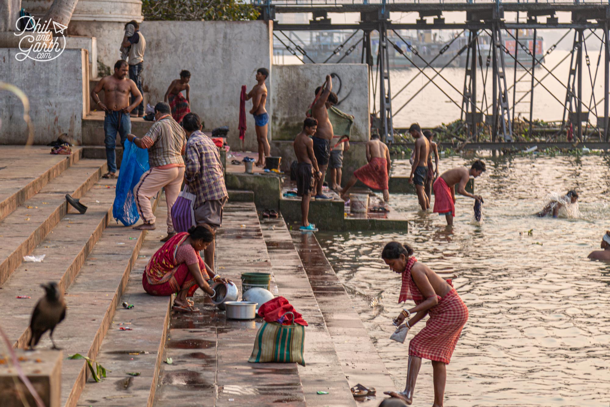 People bathing in the Hooghly River on the ghats under the Howrah Bridge Kolkata India