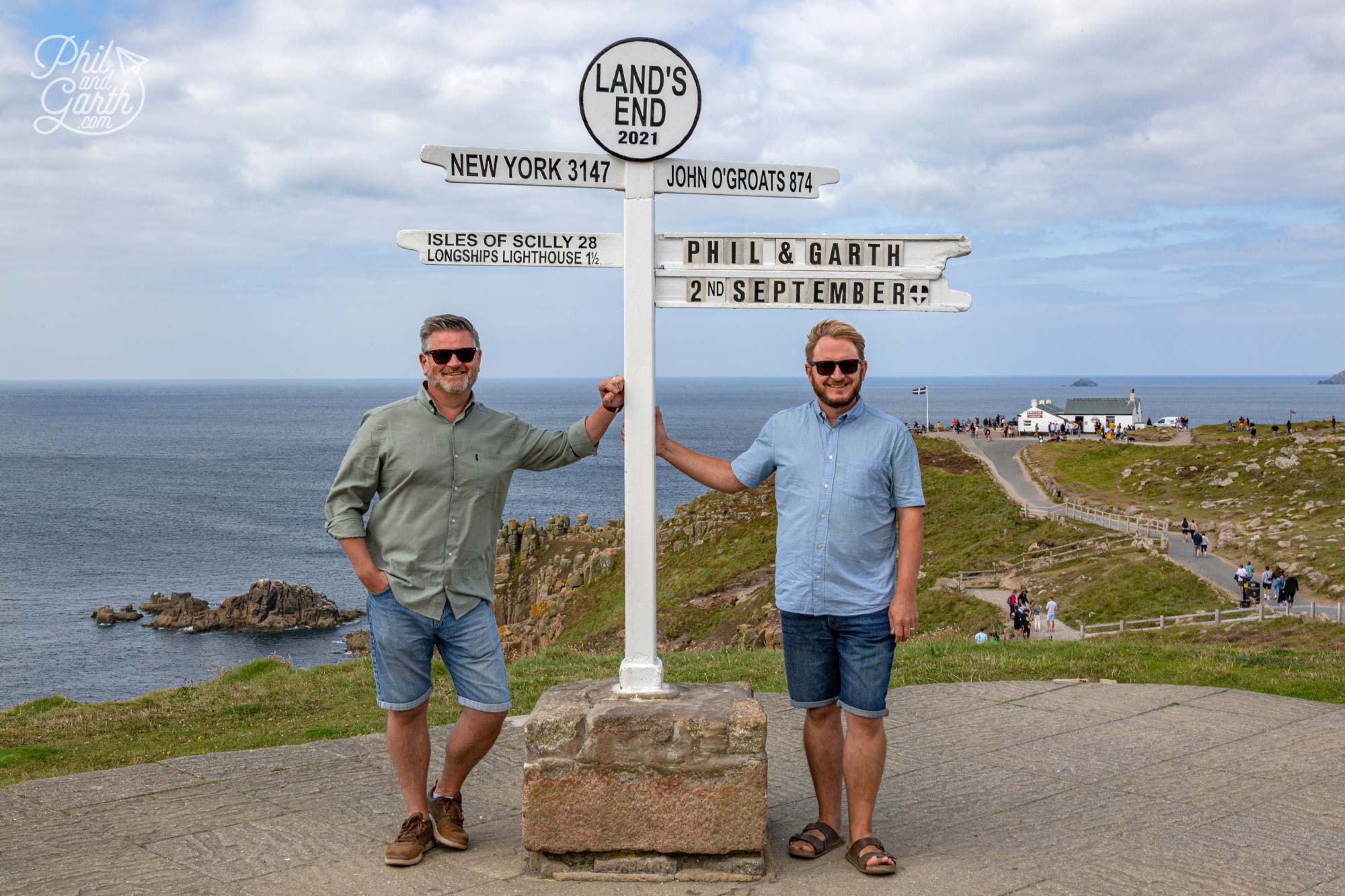 Phil and Garth stood next to the famous Land's End sign in Cornwall England