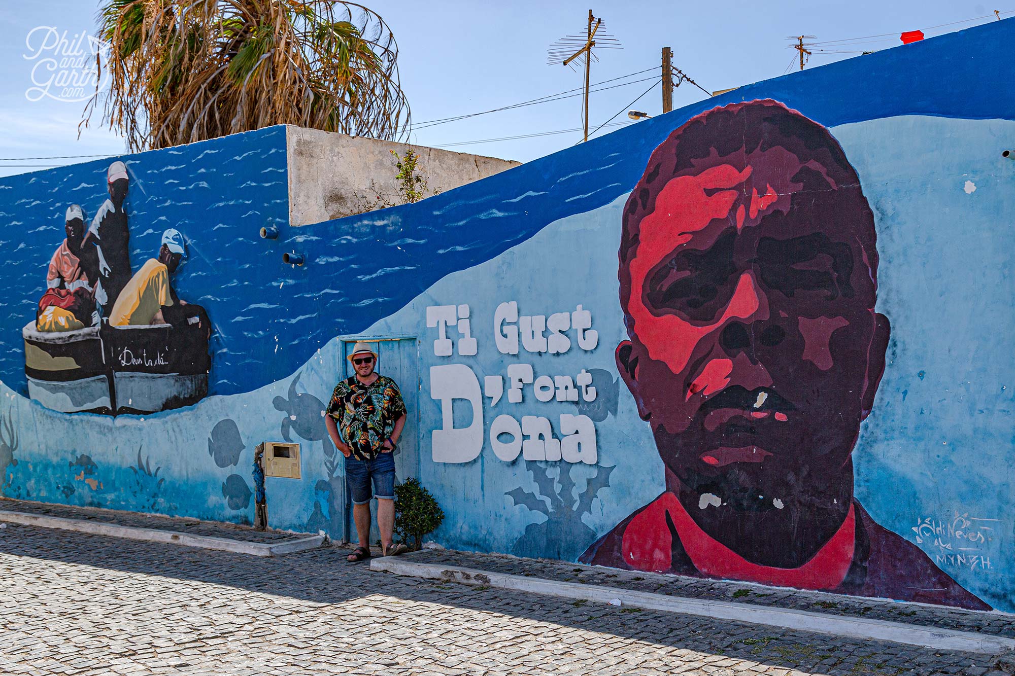 Garth infront of a mural about a local fisherman