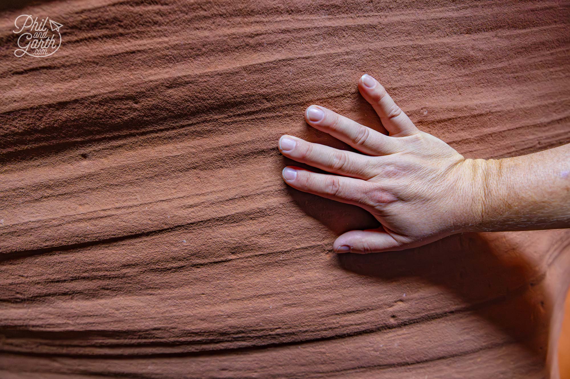 Phil touching the sandstone walls which feel soft and sponge like but are solid